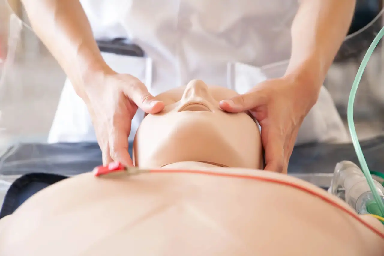 Close-up of hands on a CPR manikin's head/airway.