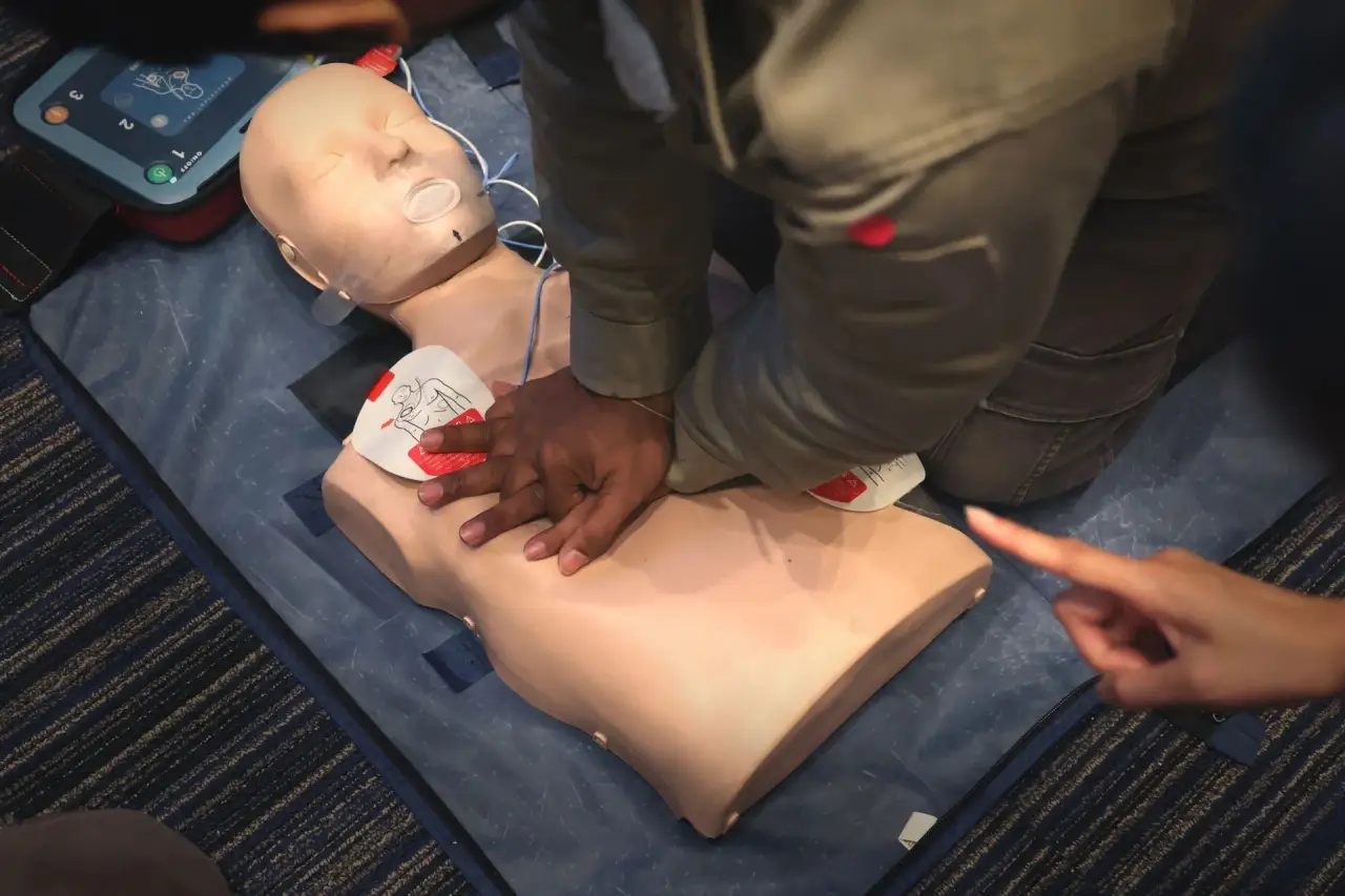 Hands practicing CPR on a manikin torso.